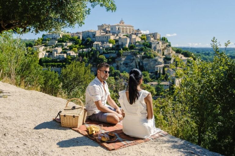 Couple enjoying a picnic overlooking the hilltop village of Gordes in Provence.