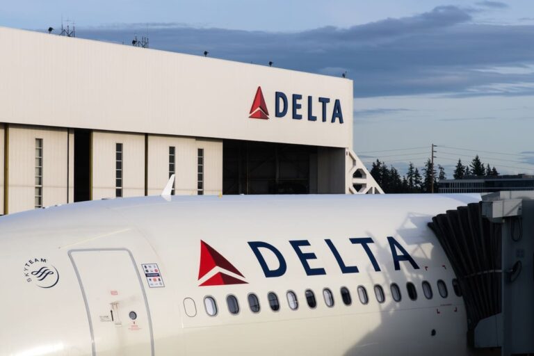 A Delta airplane parked next to a Delta gate.