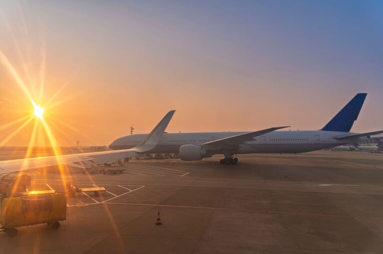Airplane taxiing on runway at sunset viewed from inside aircraft window
