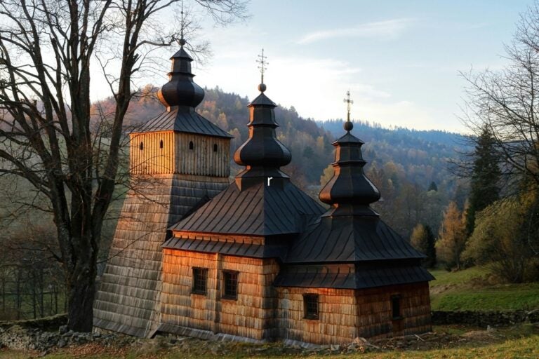 A traditional wooden Tserkva under a soft sunset glow
