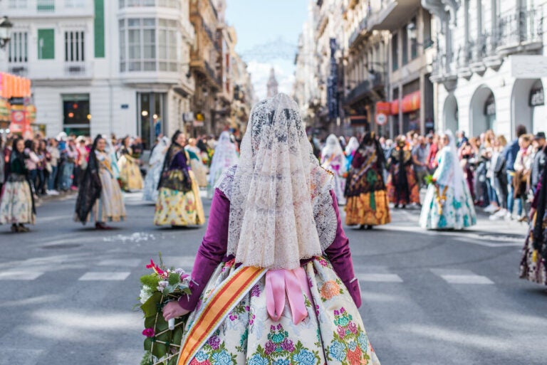 Women in traditional Valencian dress carrying flowers during the Fallas festival.