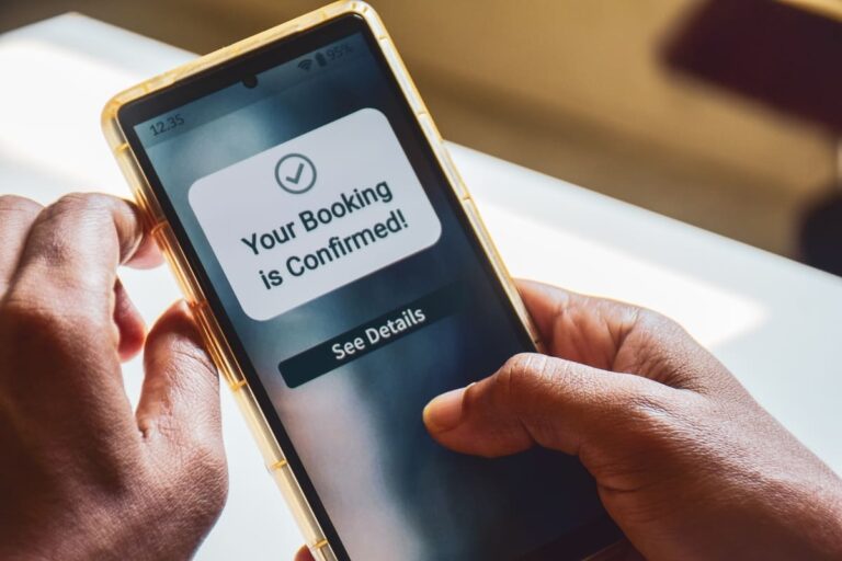 Traveler holding a smartphone displaying a confirmed flight booking notification