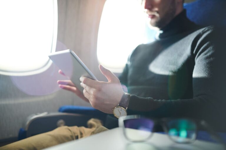 A man holding a tablet on a flight