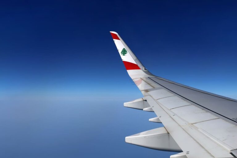 Airplane wing of a Middle East Airlines aircraft with cedar emblem visible against the sky