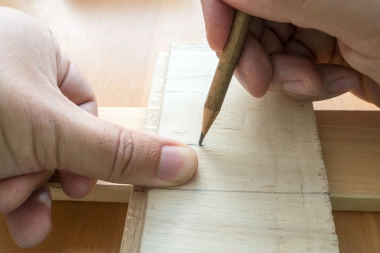 Close-up of a hand measuring wood using thumb width to illustrate a simple rule of thumb for travel timing