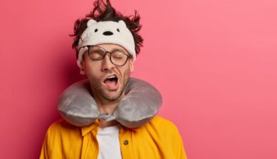 Sleepy male passenger yawning during airplane travel while experiencing jet lag