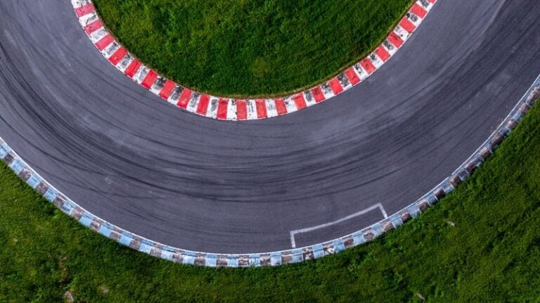 Aerial view of a sharp bend on a racetrack bordered by red-and-white curbs.