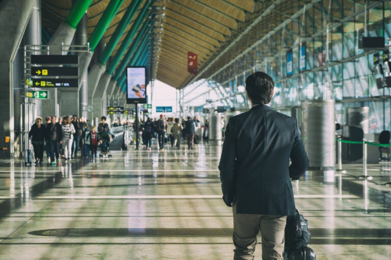 Close-up of a traveler carrying a suitcase while walking through an international airport departure terminal