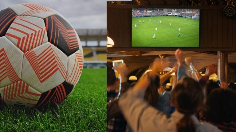 Football on a stadium pitch beside fans watching and cheering in a crowded bar.