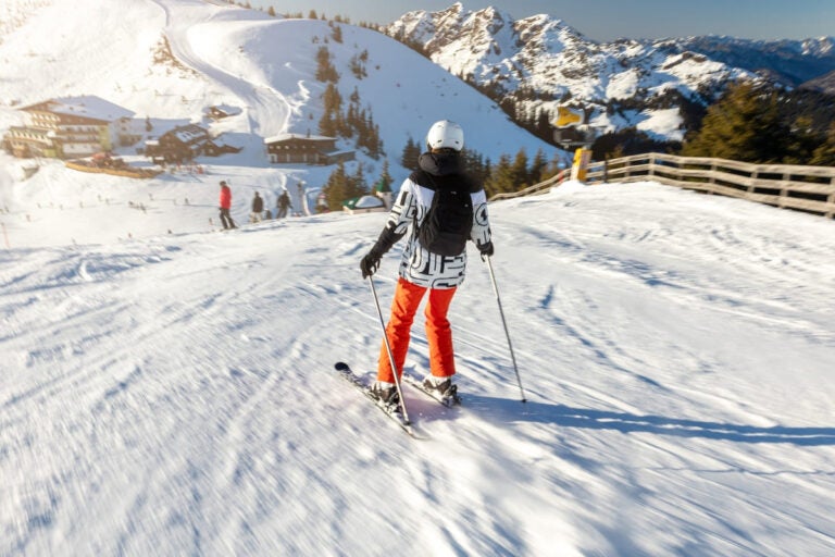 Woman skiing downhill at a snowy alpine resort in the French Alps, highlighting the winter sports culture ahead of the 2030 Winter Olympics