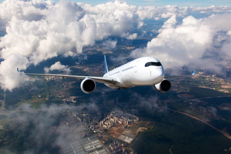 Commercial airplane flying above a city skyline representing domestic flights between Miami and Orlando