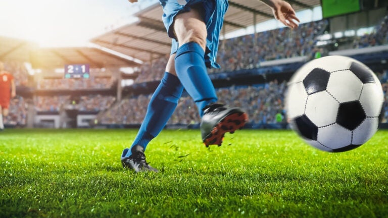 Soccer player kicking the ball in a packed stadium during an international football tournament
