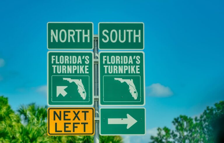 Florida Turnpike toll road sign surrounded by palm trees and blue sky