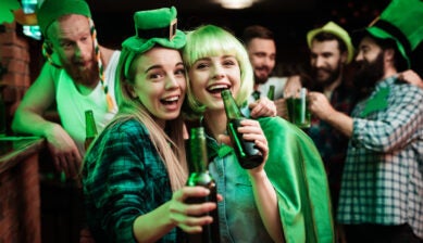 Friends wearing green accessories celebrating St. Patrick’s Day in a lively bar