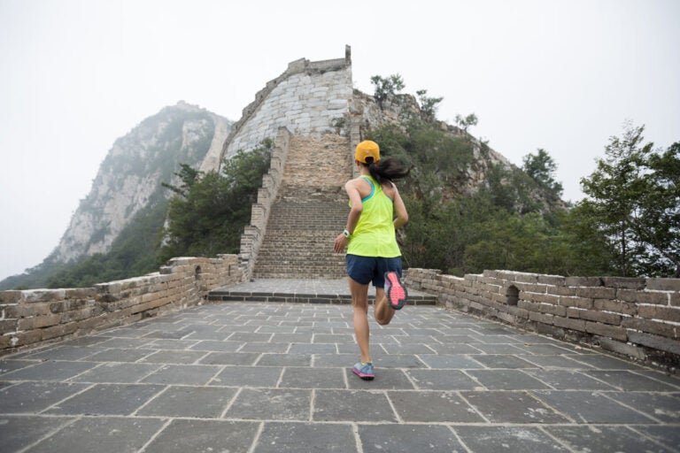 Female runner on the Great Wall of China during the Great Wall Half Marathon with mountain landscape in the background