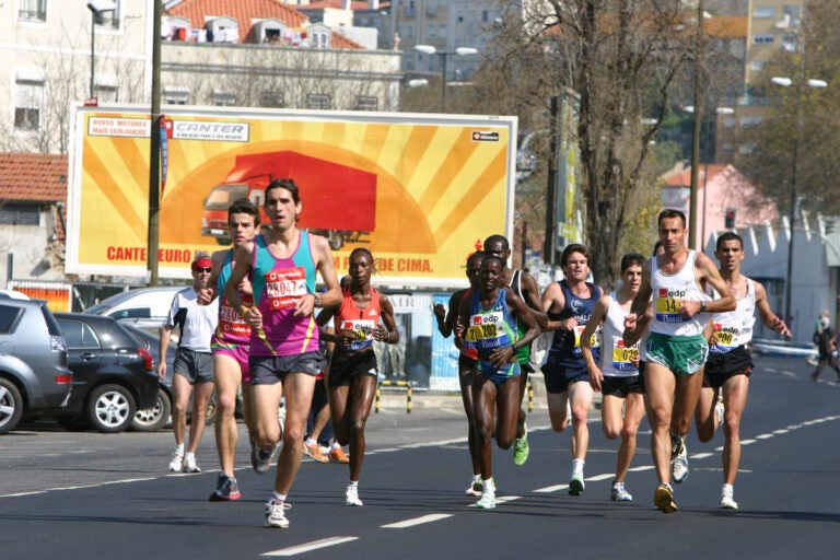 Runners participating in the Lisbon Half Marathon near the Tagus River with city skyline views