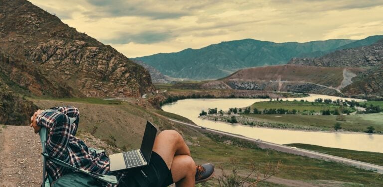 man working on his laptop while in the mountains