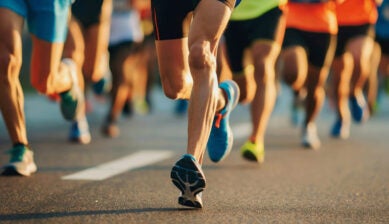 Close-up of marathon runners’ legs running on a city road during a long-distance race