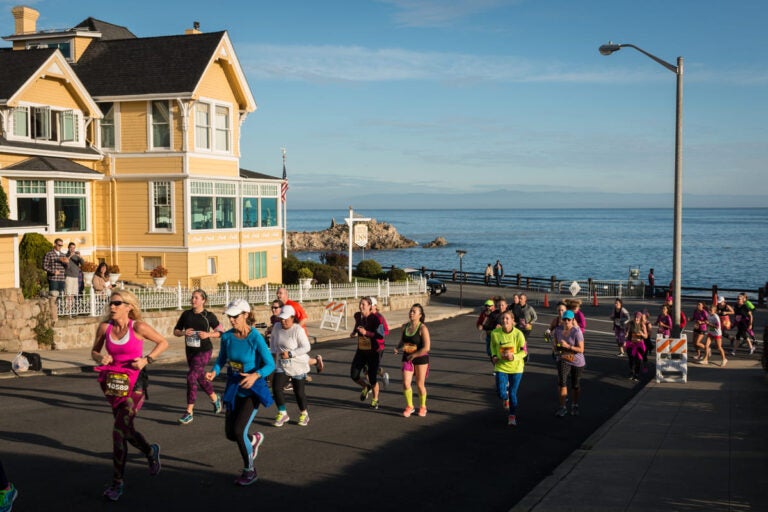 Runners climbing a coastal hill during the Monterey Bay Half Marathon with ocean views along the Pacific coastline in California