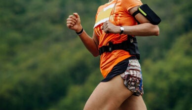 runner holding smartphone during a scenic mountain marathon trail
