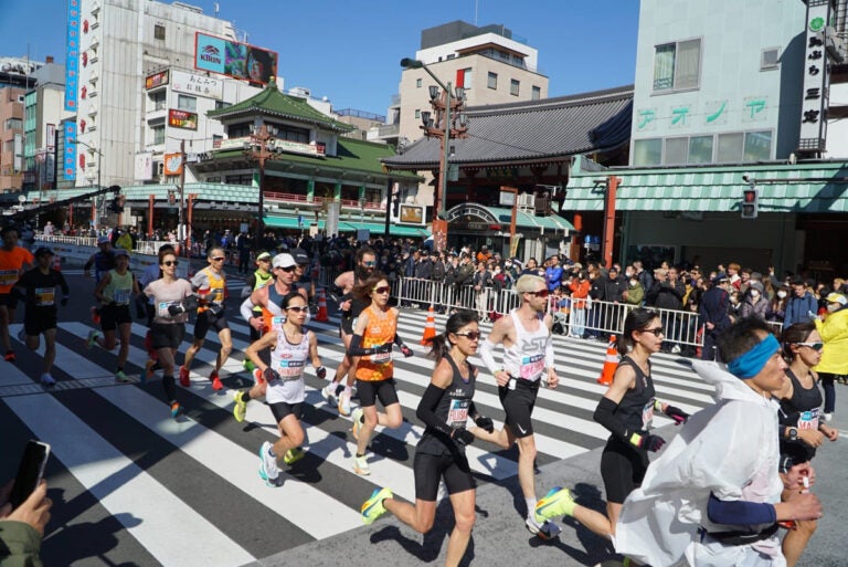 athletes running through tokyo city streets during the tokyo marathon