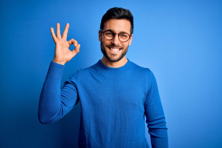 Traveler smiling and making an OK hand gesture symbolizing a successful travel plan