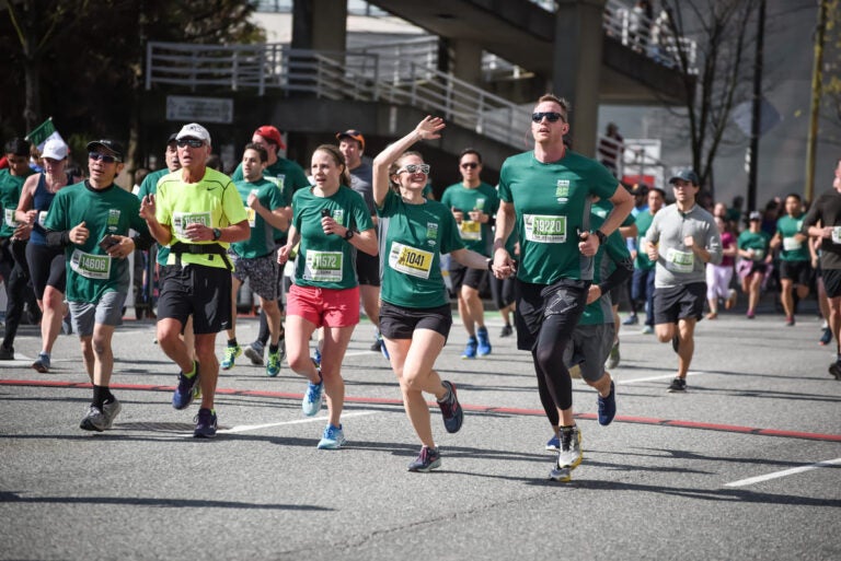 Runners participating in a road race in Vancouver with oceanfront and city scenery