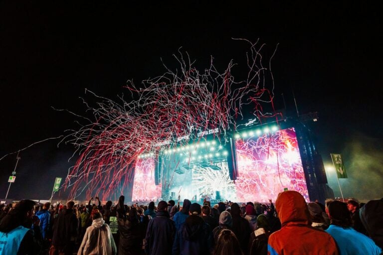 Rock am Ring lit in vibrant pink with red and white streamers shooting into the air. 