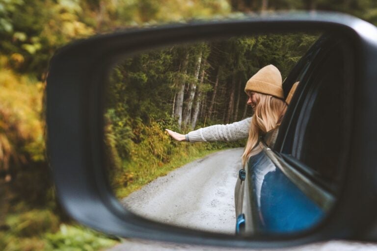 A woman enjoying the scenery while driving through Canada in a rented car.
