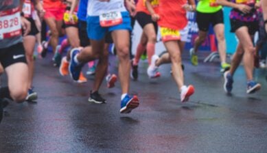A large crowd of marathon runners in motion on city streets at the start of a race