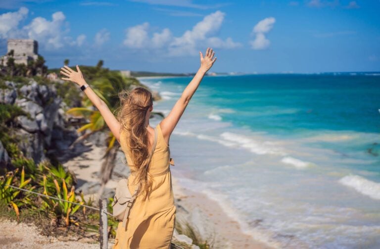 woman lifting her arms close to a beach in cancun