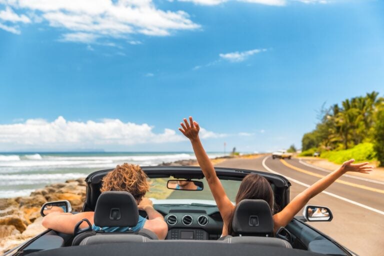 A couple driving along the coast in Vancouver in a rented car.