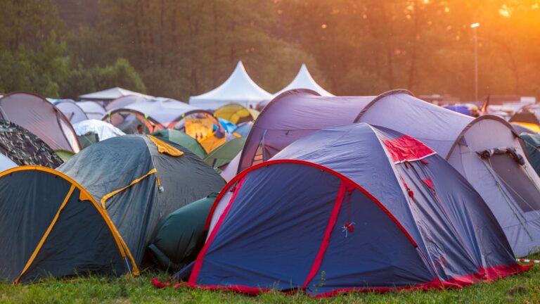 Rows of colorful tents at a sunny Coachella festival campsite