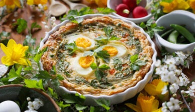 Easter quiche tart with boiled eggs, vegetables, and herbs in a casserole dish close up