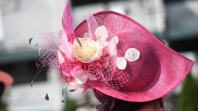 Elegantly dressed racegoers wearing large decorative hats at the Kentucky Derby grandstand