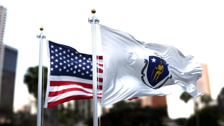 Massachusetts state flag waving with the American flag blurred in the background