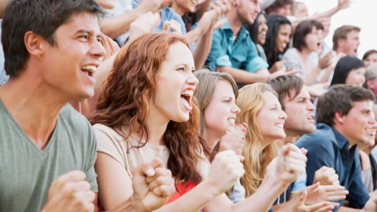 Excited fans cheering in the grandstand crowd at a major sporting event