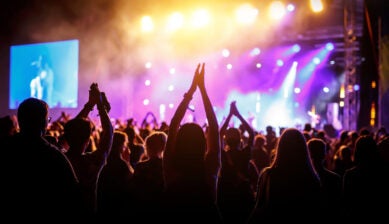 Happy crowd of people with hands raised at a live music festival stage in summer