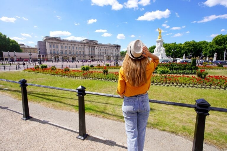 A young woman looking at Buckingham Palace, UK. Source: Shutterstock.