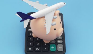 Miniature airplane and piggy bank on a calculator representing travel budget savings