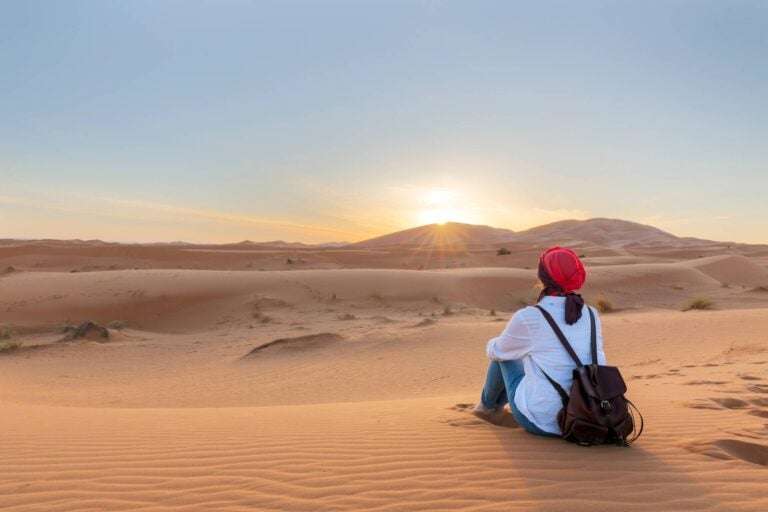 woman sitting at the sahara desert with the sunset in tunisia