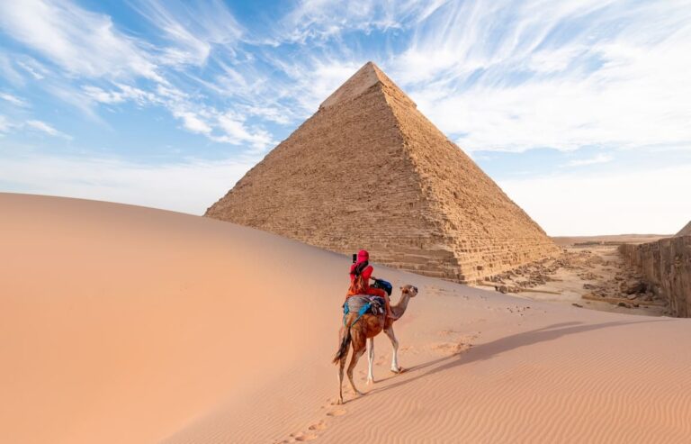 Woman in red turban riding a camel near the Giza Pyramid Complex in Cairo, Egypt