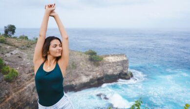 Young woman standing on a cliffside in Nusa Penida, Bali, overlooking the ocean