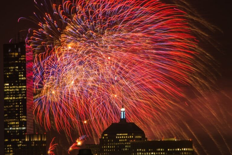 Fireworks go off over the city of Boston.