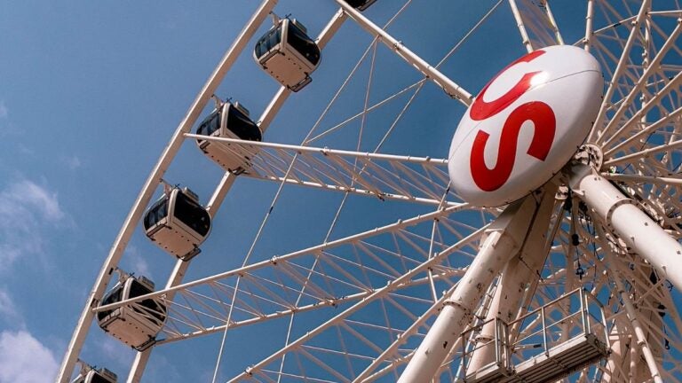 A ferris wheel on the midway at the Calgary Stampede fairgrounds against a blue sky