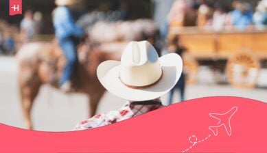 A cowboy in a plaid shirt and white hat watching a rodeo event at the Calgary Stampede