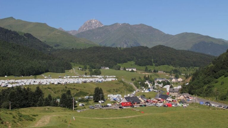 Crowds of fans gathered on a green mountain pass to watch a cycling stage