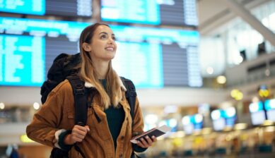 Excited woman traveler at the airport holding a passport and travel documents, ready for an international flight