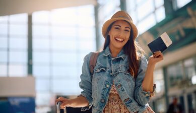 Happy woman holding her passport and plane ticket at an airport departure area