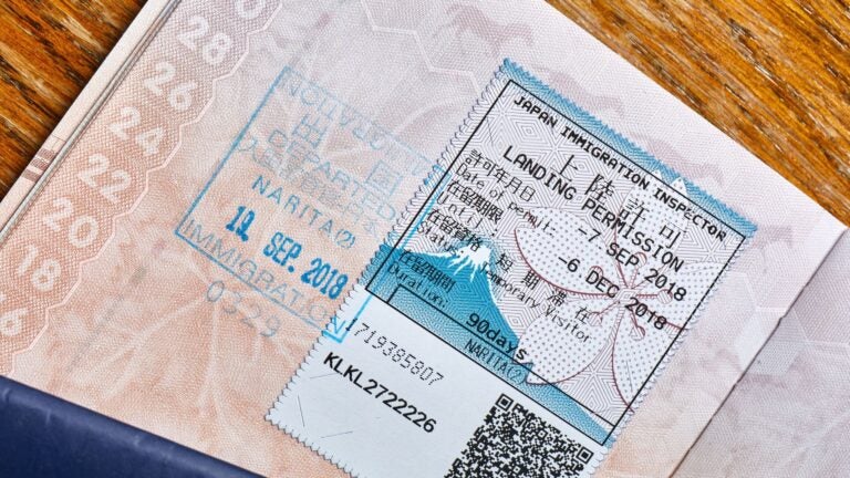 A blue passport open to a page showing an official Japanese entry stamp.